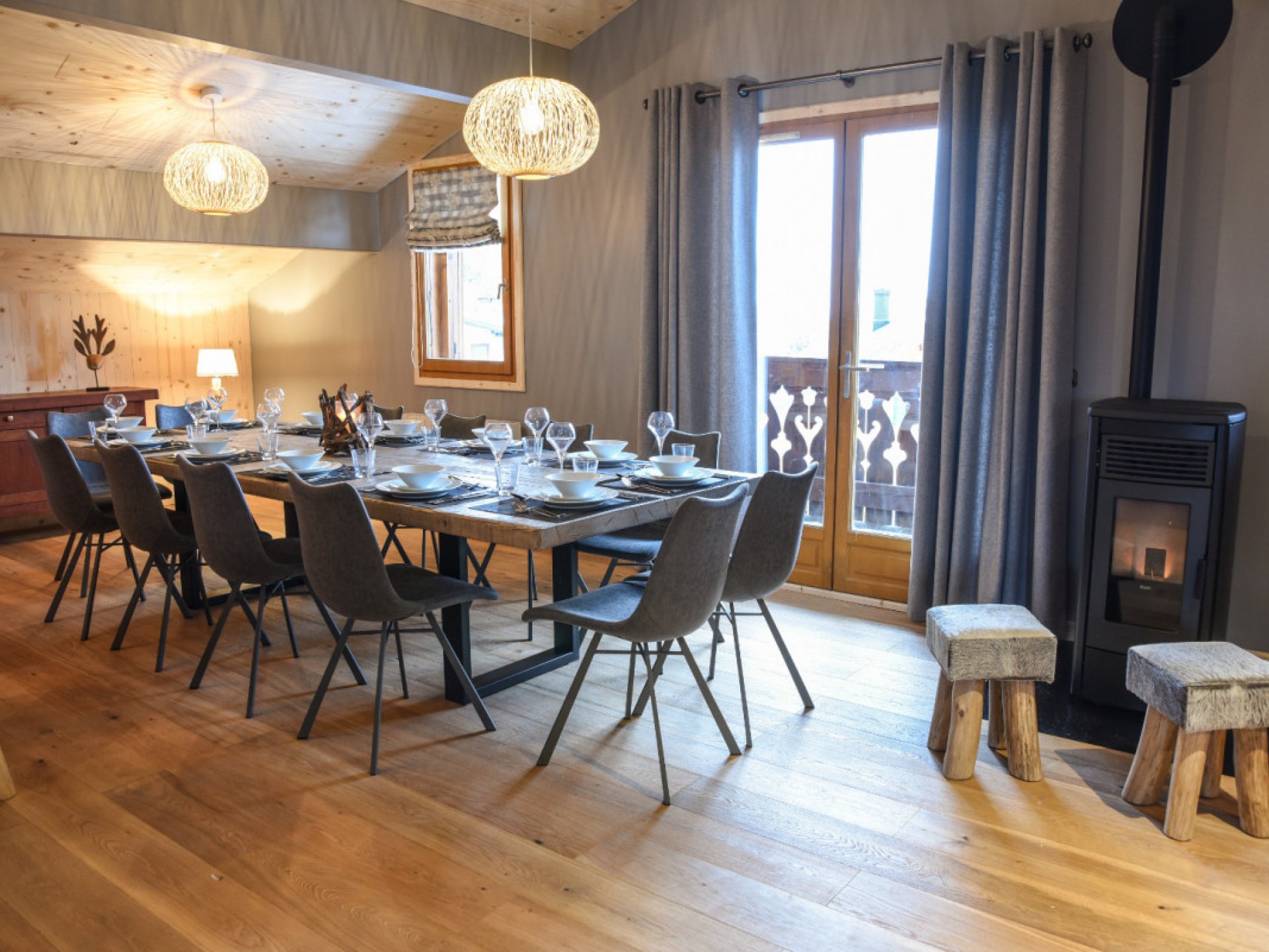 Dining room in a chalet with laid table, and windows overlooking the mountains