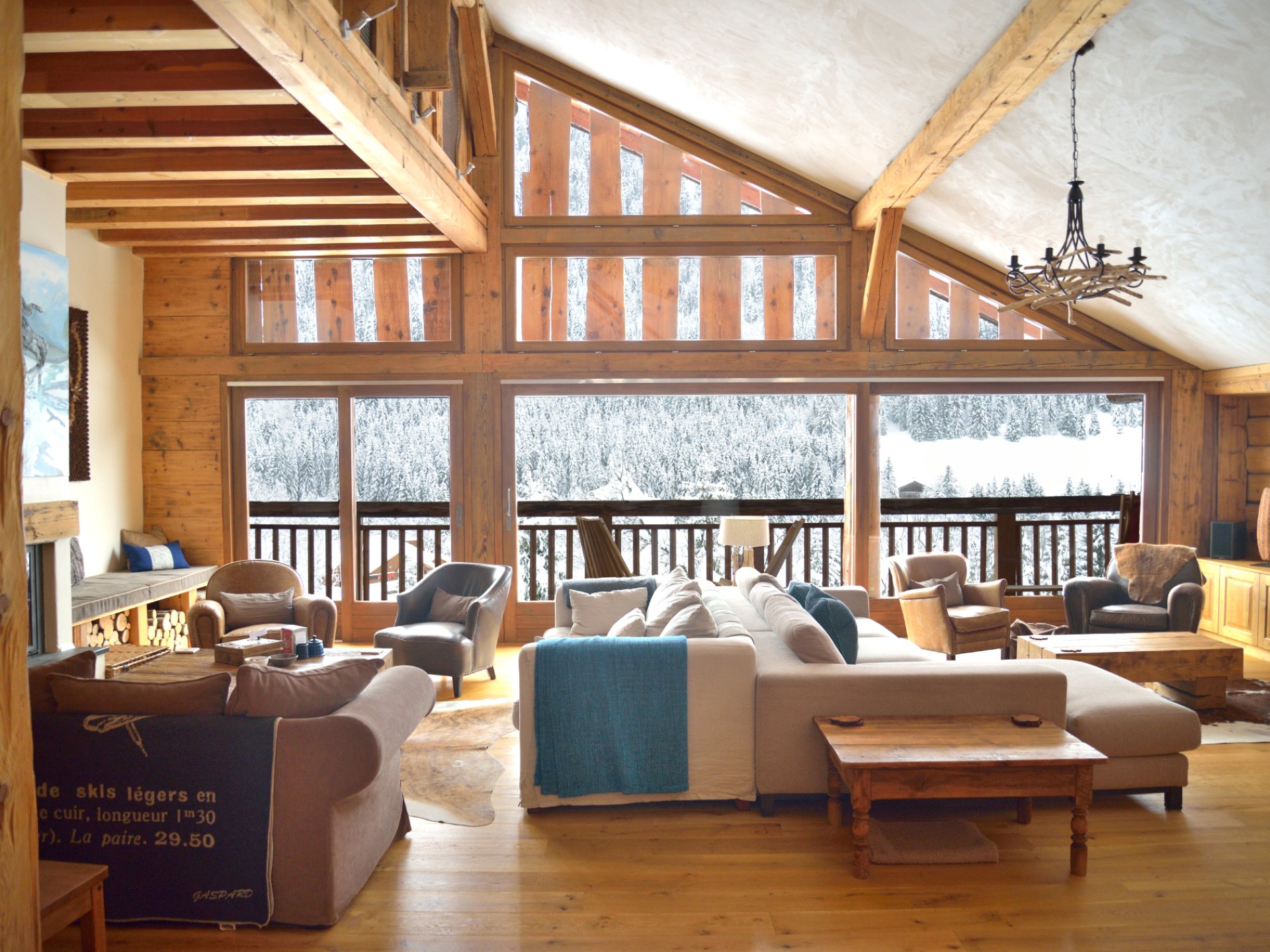 Chalet living area with large window feature overlooking snowy mountains.